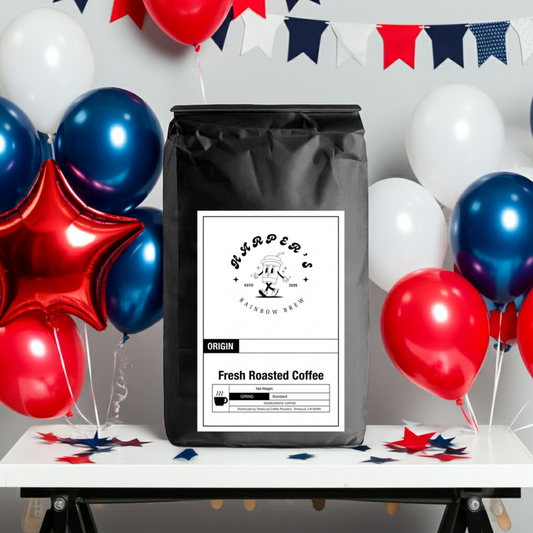 Front view of Harper's Rainbow Brew Fresh Roasted Coffee in a black bag, surrounded by red, white, and blue balloons.